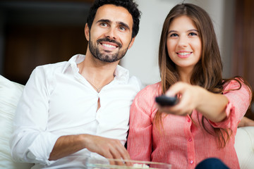 Young couple watching tv and eating pop-corn