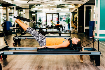 Woman exercising on a reformer bed