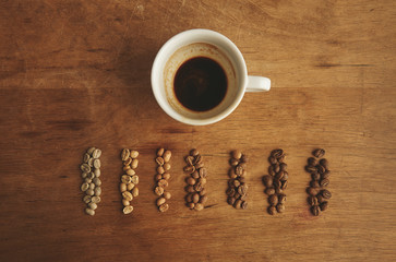 Grades roasting coffee near espresso cup wooden table top view