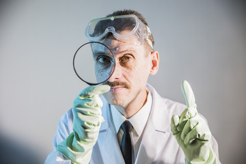 funny engineer inventor scientist looks through a magnifying glass and and raised his index finger