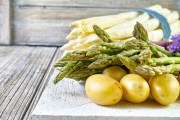 Bunch of fresh potatoes and asparagus on wooden table