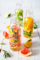 Selection of infused water in glass bottles, rustic wood background