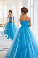 Naklejka premium Beautiful bride in gorgeous blue dress Cinderella style in a morning near mirror