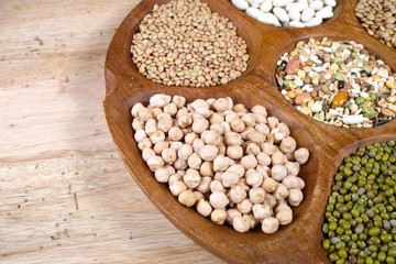 Wooden bowl of various legumes on wooden background copy space