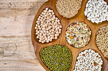 Wooden bowl of various legumes on wooden background copy space