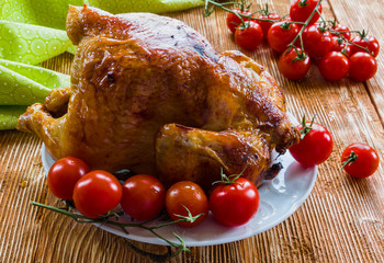 Poultry : homemade roast whole chicken with  tomatoes on wooden background.