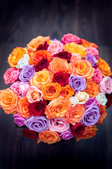 big round bouquet of colorful roses on a background dark wood