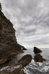 Rocks and cliff in the mediterranean sea on a cloudy day.
