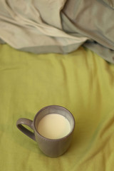 Cup of yogurt on the bed with green sheets. Selective focus. 