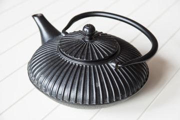 Black Chinese cast iron teapot to brew green tea on white table