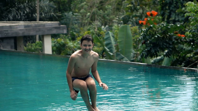 Happy boy jumping into swimming pool, super slow motion 240fps
