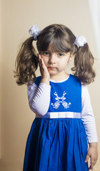 Small Caucasian girl putting her hand on her cheek Posing with blue dress standing inside studio