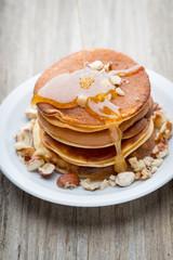 Stack of homemade pancakes with honey on wooden background.