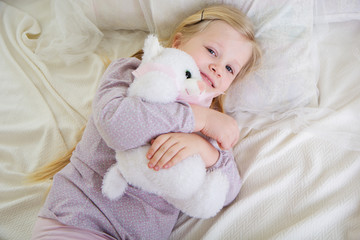 Child girl in the bed with teddy bear