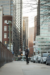 Fototapeta na wymiar Full back figure of a skateboarder cruising down city street bef