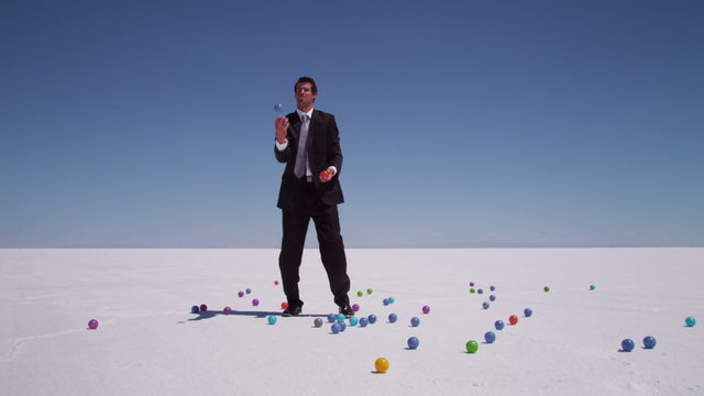 Businessman juggling balls at salt flat