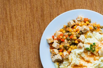 Healthy vegetarian cuisine with tofu with colorful roast vegetables including carrot, peas and maize served with mashed potatoes. Top view