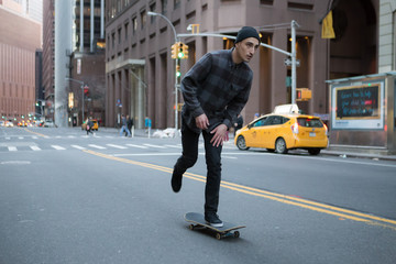 Young skateboarder cruising donw the city street before sunset.