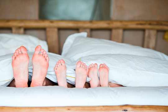 Feet Of Family In Bed