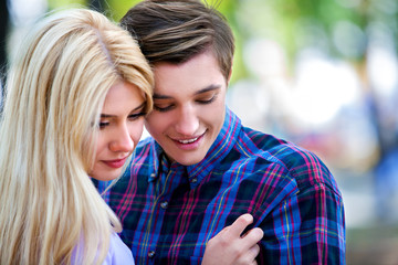 Young couple looking down hugging and flirting in  park  spring outdoor and looking away.