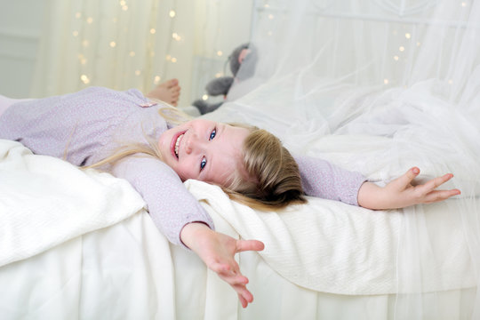 Pretty child is lying down in the white bed