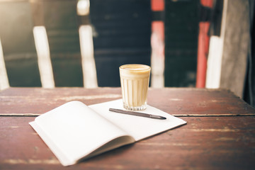 Opened blank notepad, pen and cup of coffee on wooden table