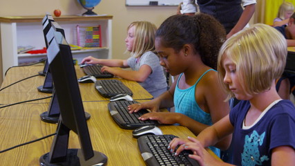 Elementary school teacher helps students with computers - Powered by Adobe