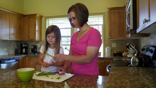 Mother and daughter in kitchen cutting green beans