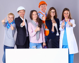 Portrait of smiling people with various occupations holding blank billboard showing ok