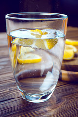 Glass of pure mineral water with lemon on wooden table