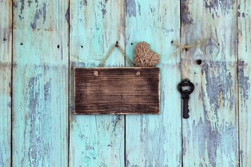 Blank rustic sign with heart and antique key hanging on teal blue wood background