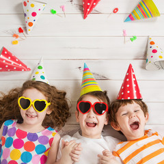 Happy child friend in carnival party, lying on a wooden floor.