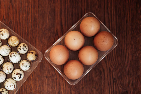 A goose egg, hen egg and a quail egg on a wooden background.