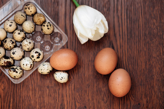 A goose egg, hen egg and a quail egg on a wooden background.
