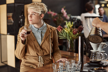 Trendy young woman daydreaming in a cafe with coffee