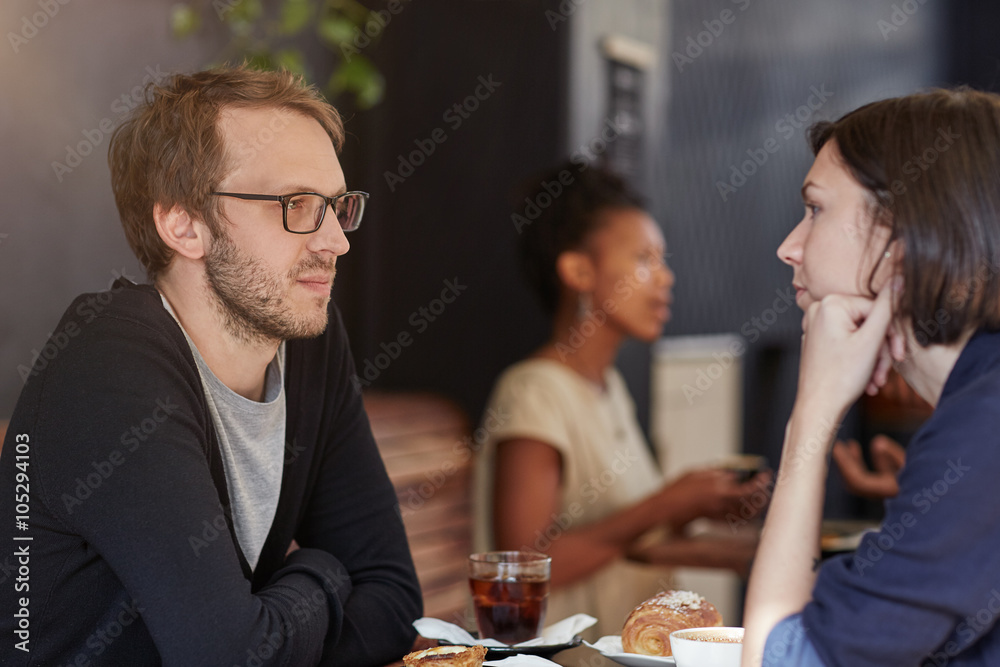 Wall mural Man looking serious at a cafe table with female companion