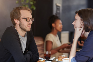 Man looking serious at a cafe table with female companion