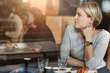 Woman sitting in cafe looking away wearing a trendy watch