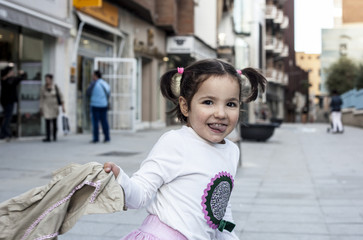 Obraz premium Happy three year old girl playing with her coat in the city
