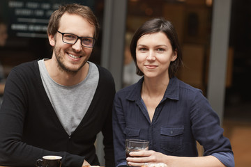 Modern couple smiling outside a modern cafe with coffee