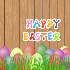 Easter eggs in the grass on a wooden background.