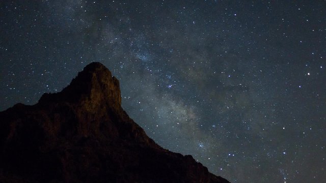 Milky Way stars move behind a desert mountain - time lapse