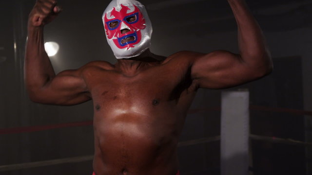 Masked wrestler flexing muscles and intimidating opponent