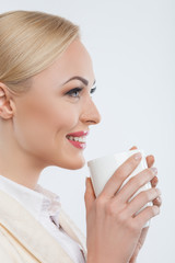 Cheerful young businesswoman is enjoying hot tea