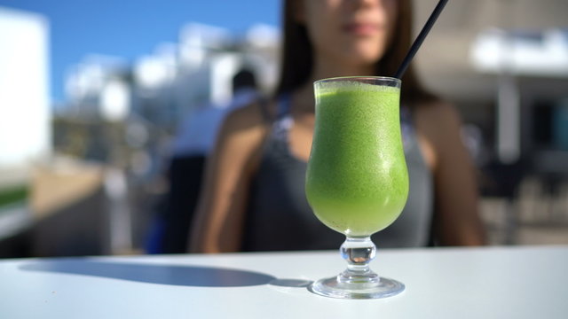 Healthy eating concept - green smoothie breakfast at outdoor city cafe or restaurant terrace. Closeup of vegetable juice on table with unrecognizable person in the background for a detox cleanse diet.