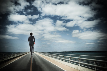 まっすぐな道路を歩くビジネスマン