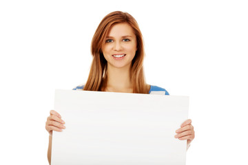 Happy teenage woman with blank billboard