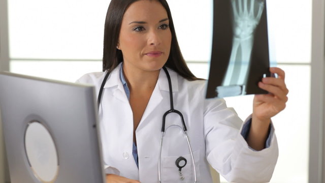 Female doctor reviews x-ray at desk