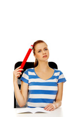 Teenage woman doing homework and holding huge pen