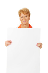 Fototapeta premium Smile elderly female doctor or nurse holding blank banner